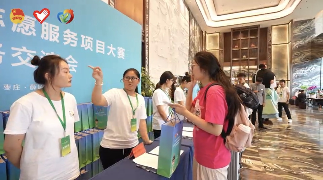 圖為”新奇“實踐團(tuán)成員指引參賽者會場方向